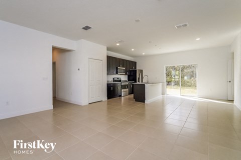 an empty living room and kitchen with white walls and tiled floors