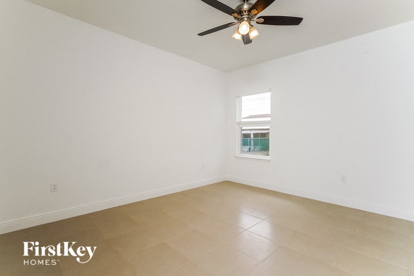 a empty living room with a ceiling fan and a window