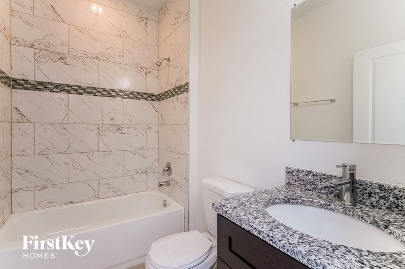 a bathroom with a tub sink and toilet and a mirror