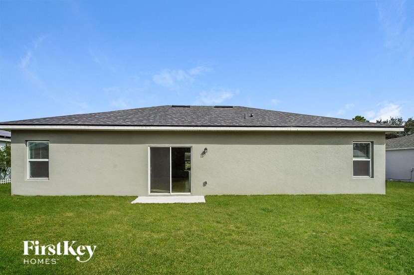 the backyard of a white house with a lawn and a blue sky