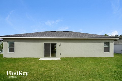 the backyard of a white house with a lawn and a blue sky