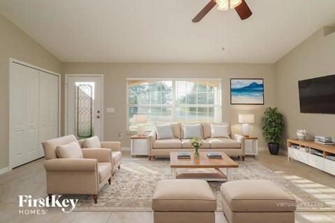A living room with a beige sofa set, a coffee table, and a ceiling fan.