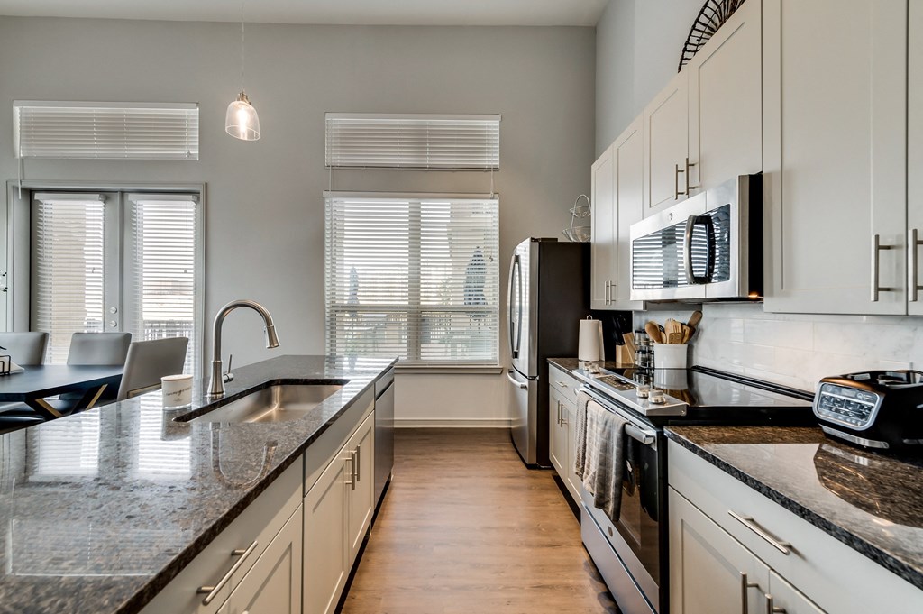 an updated kitchen with granite counter tops and white cabinets
