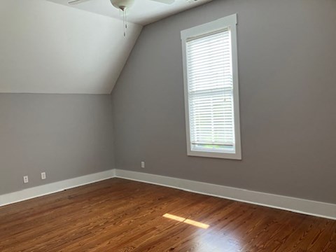 an empty room with a window and wooden floors