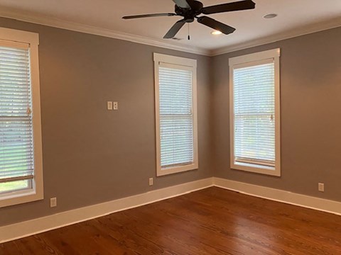 a empty room with a ceiling fan and three windows