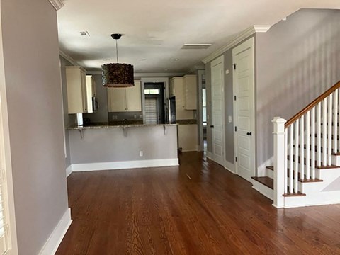 an empty living room with a kitchen and a staircase
