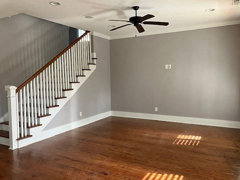 a empty living room with a staircase and a ceiling fan