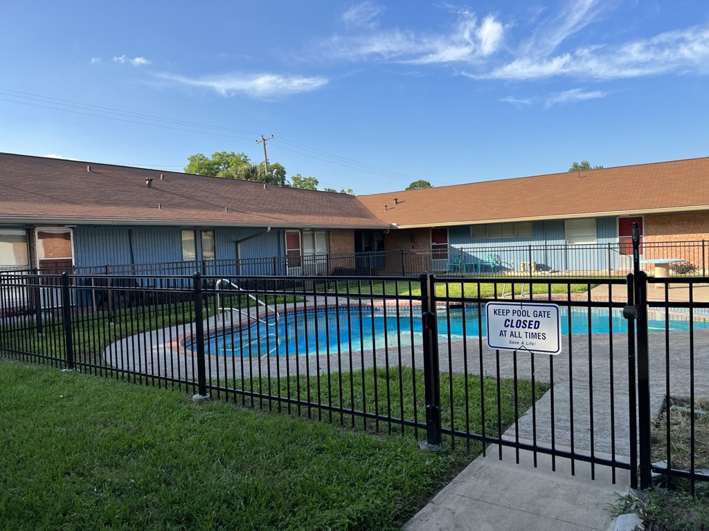 A pool surrounded by a black fence with a sign that says to keep the pool closed at all times.