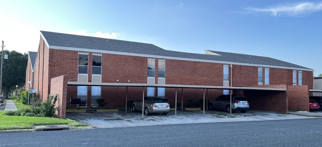 A red brick building with a parking lot in front.