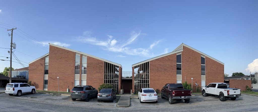 A parking lot with cars and a building in the background.