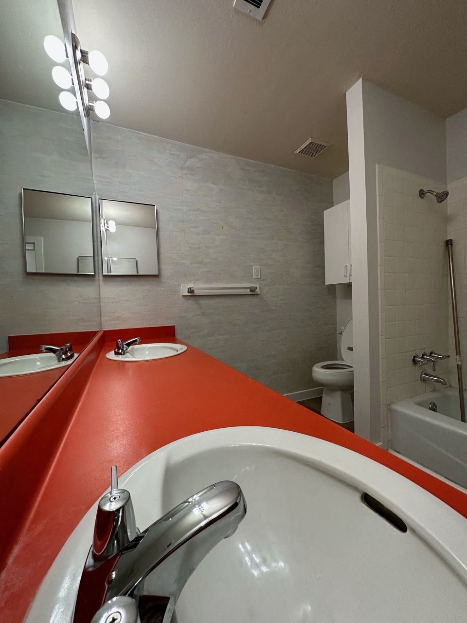A public bathroom with red counter tops and white sinks.