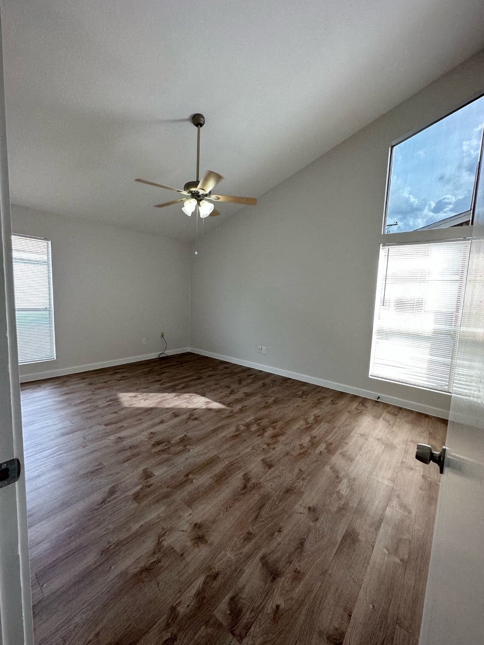 A room with a ceiling fan and wooden flooring.