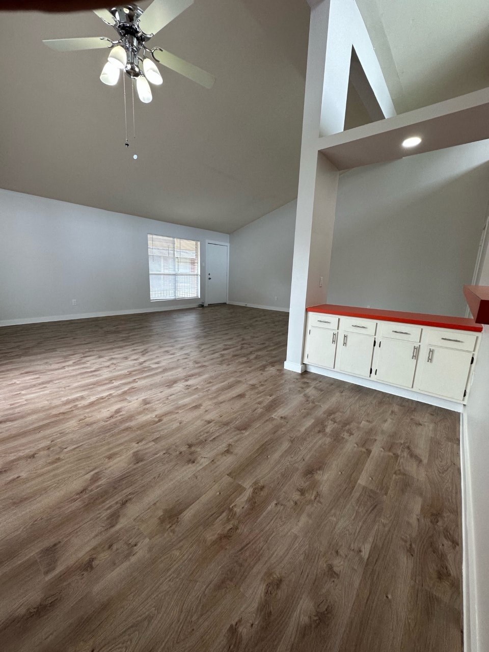 A room with a ceiling fan and wooden flooring.