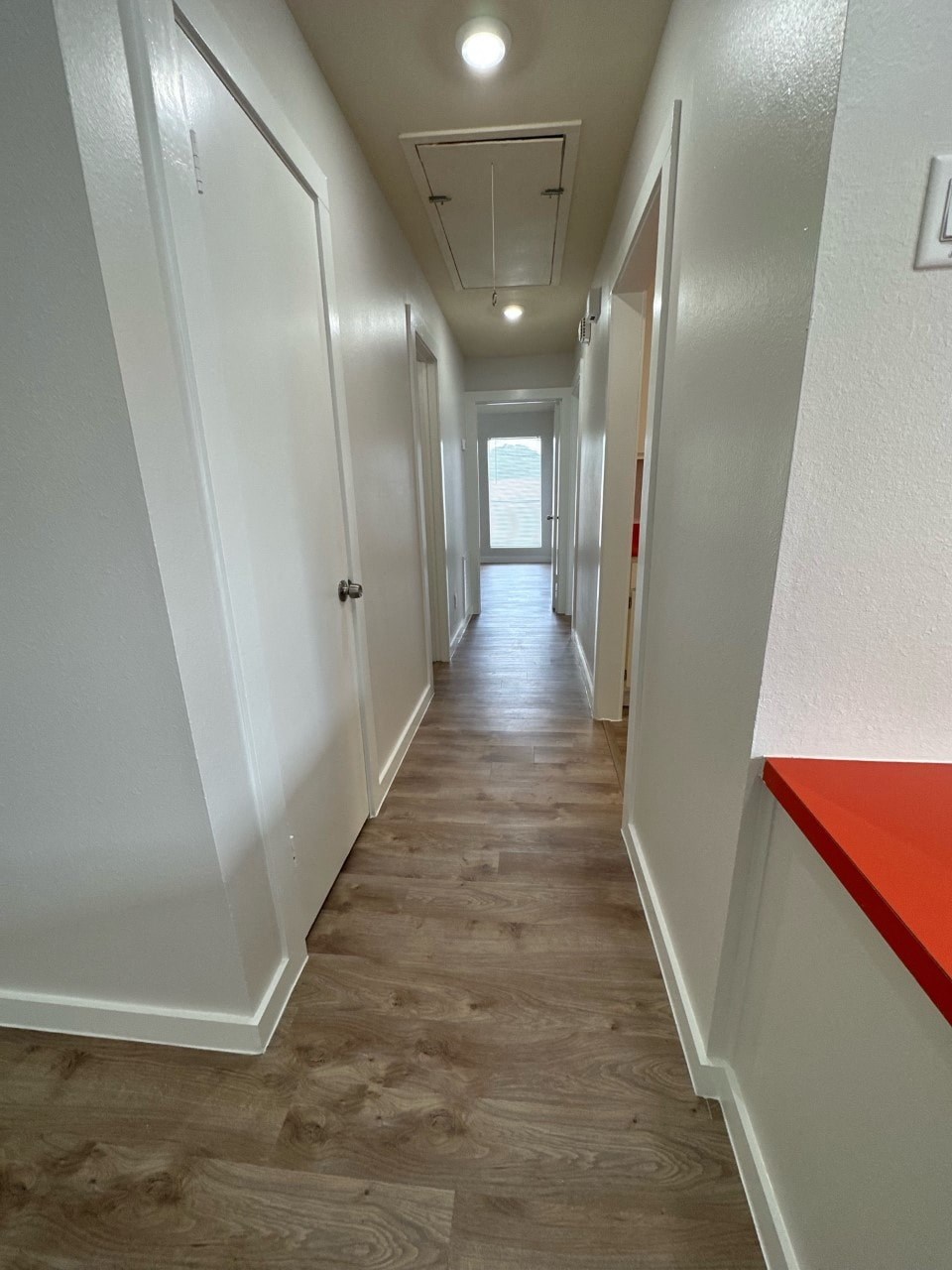A long hallway with white walls and wood flooring.