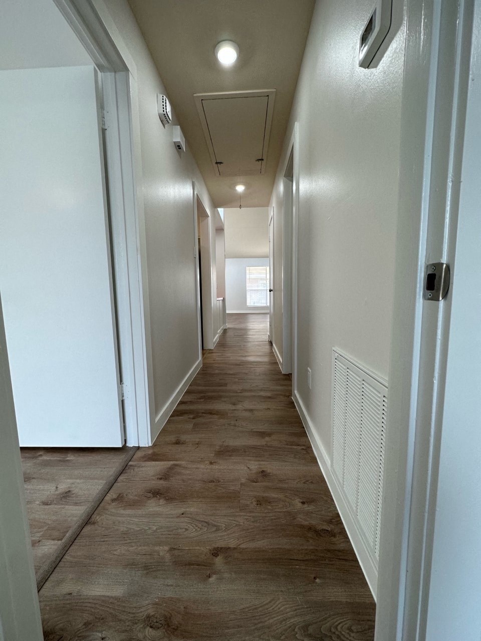 A long hallway with white walls and wood flooring.