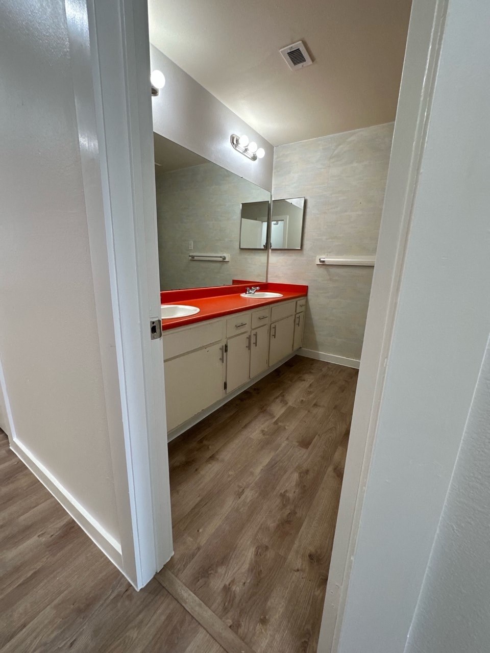 A bathroom with a red countertop and white cabinets.
