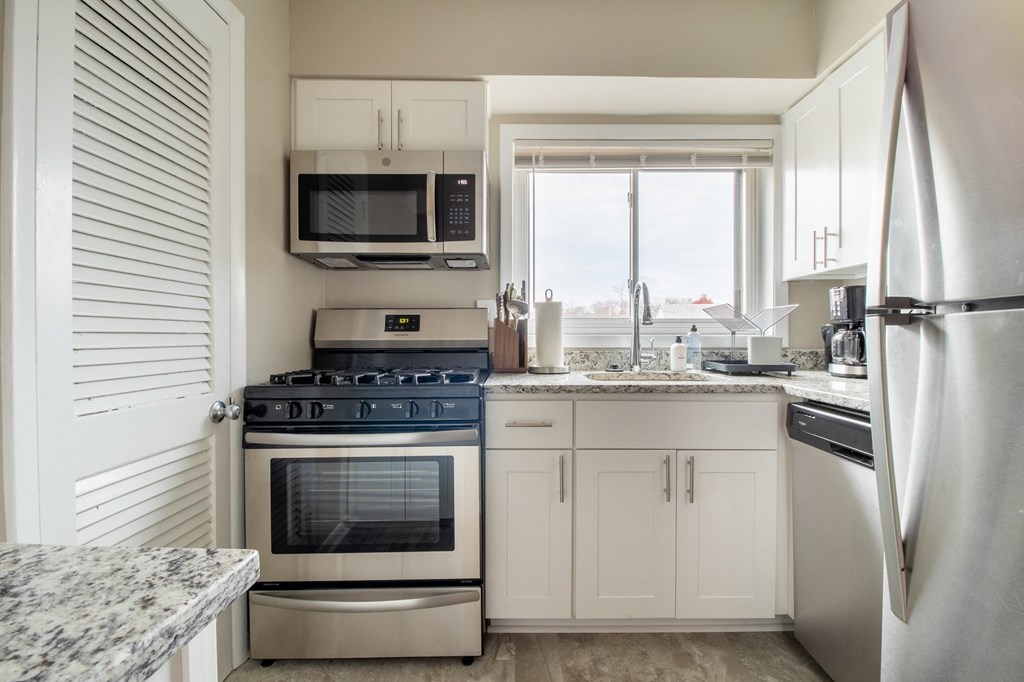 a kitchen with white cabinets and stainless steel appliances and a window