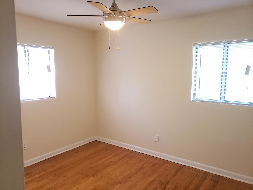a bedroom with a ceiling fan and two windows