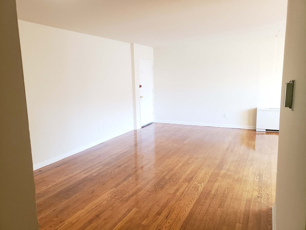 an empty room with white walls and wooden floors