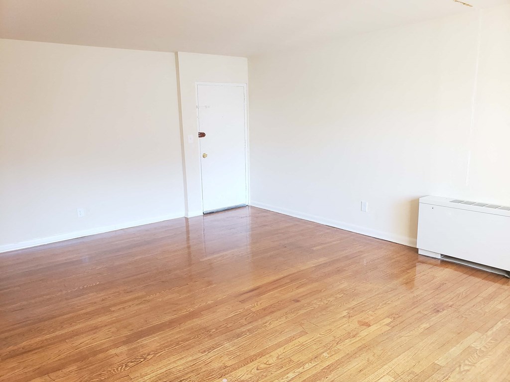 an empty room with a hard wood floor and a refrigerator