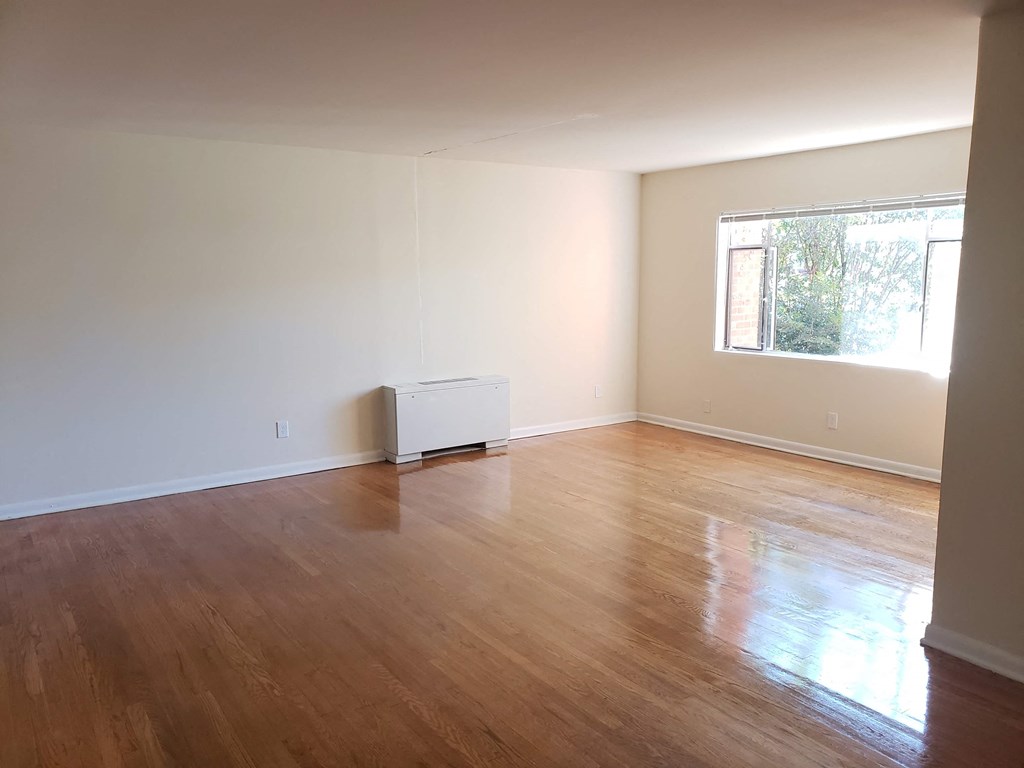 an empty living room with wooden floors and a window