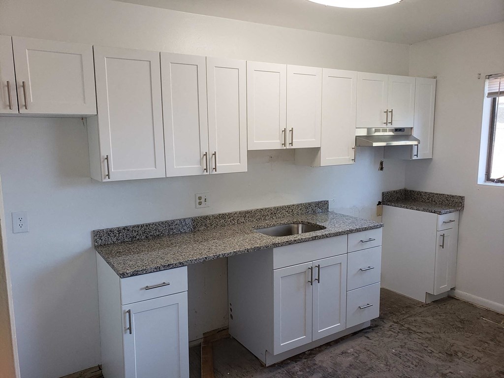 a kitchen with white cabinets and granite counter tops