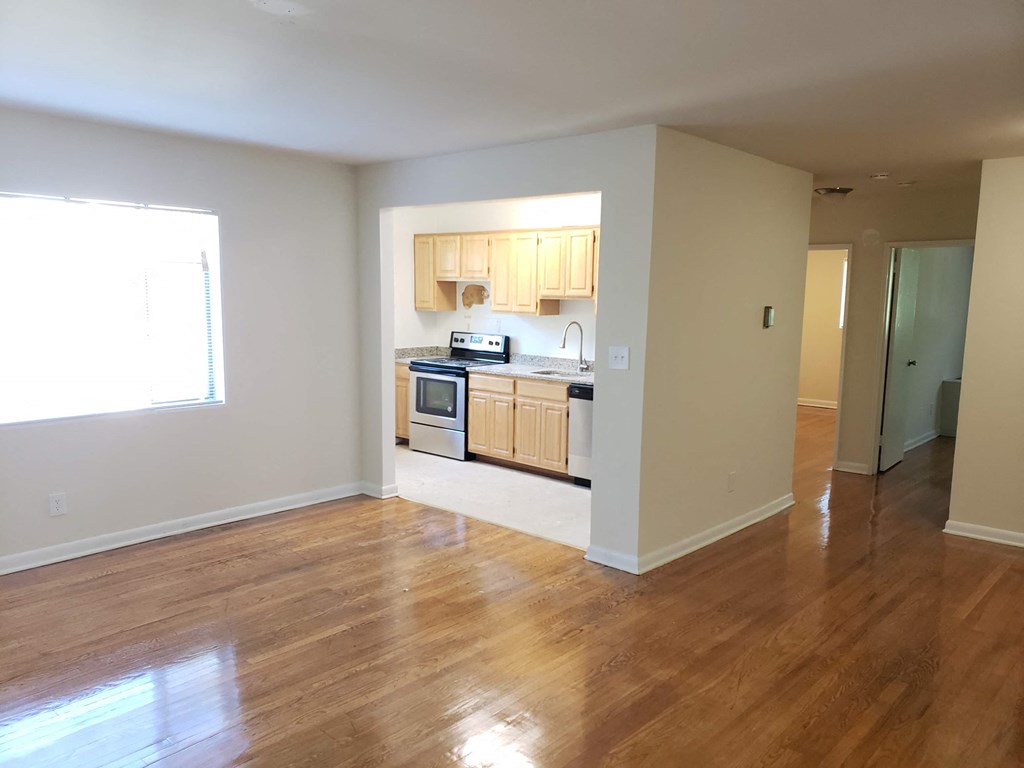 an empty living room and kitchen with wood flooring