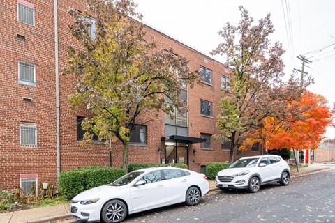 a brick apartment building with two cars parked in front