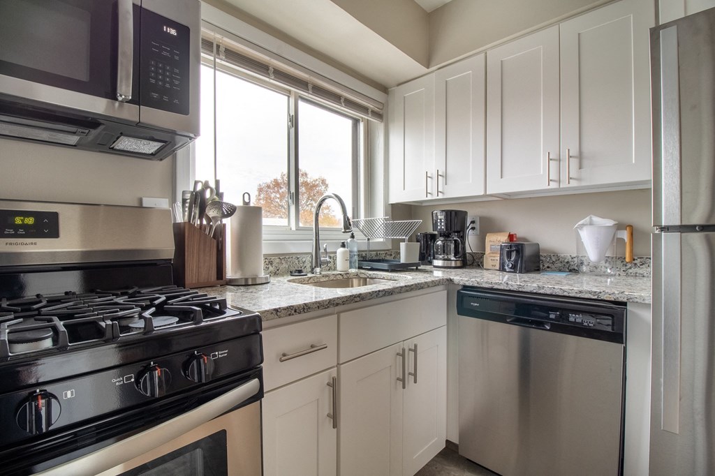 a kitchen with white cabinets and stainless steel appliances and a window