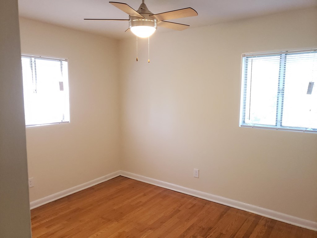 a bedroom with a ceiling fan and two windows