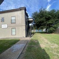 the front of a house with a yard and a tree