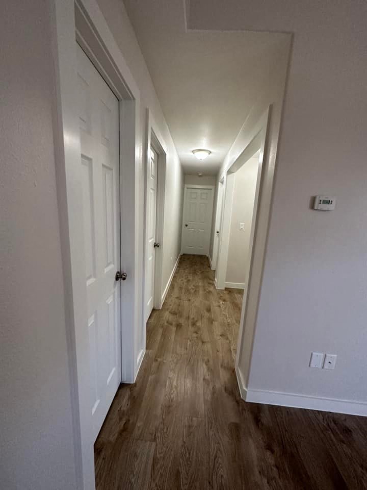 a hallway with white walls and wooden floors and a white door
