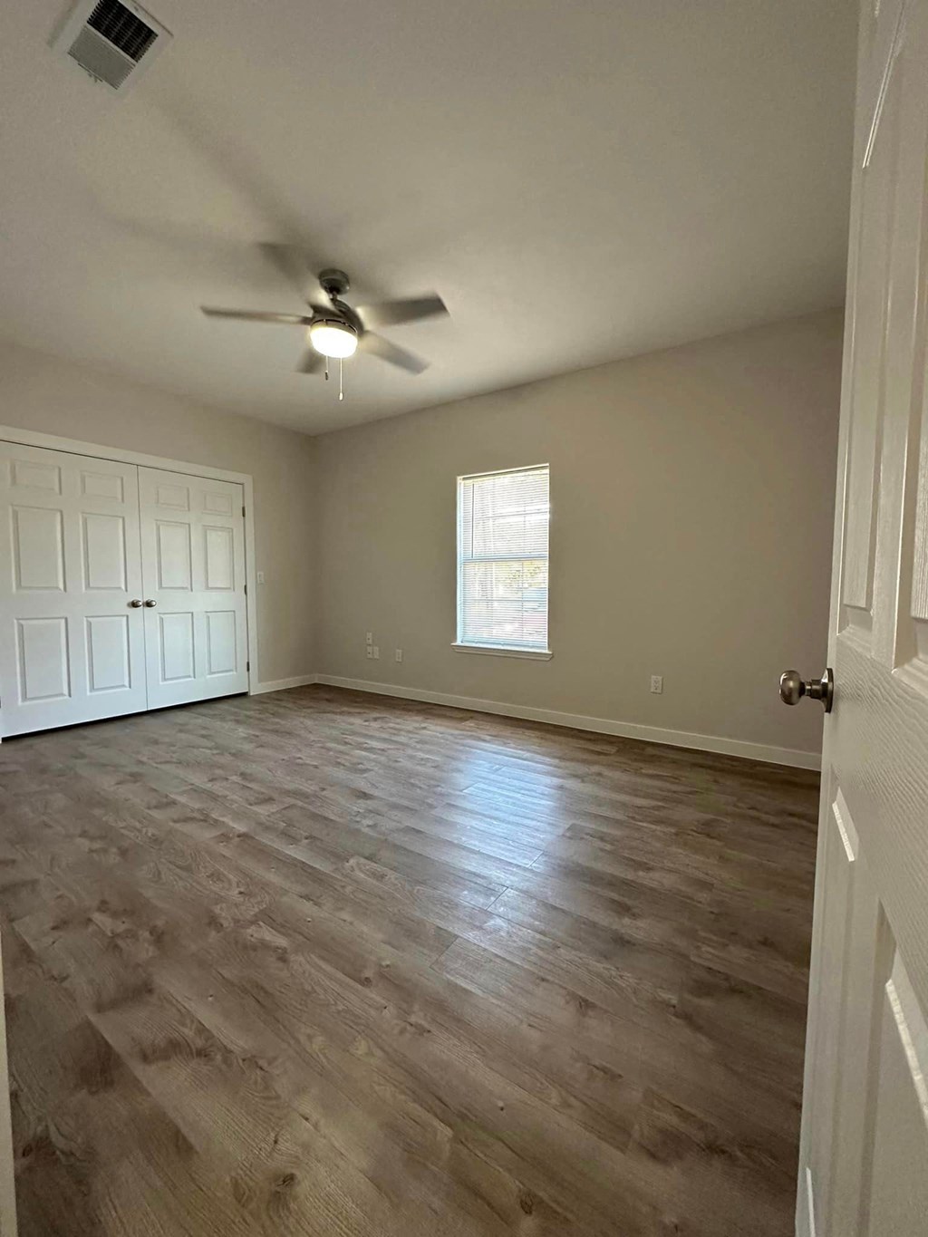 an empty living room with a ceiling fan and wood floors