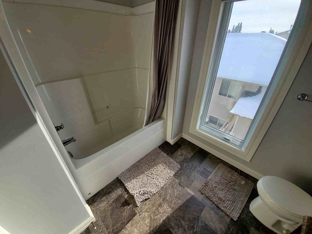 a bathroom with a shower and a toilet next to a window