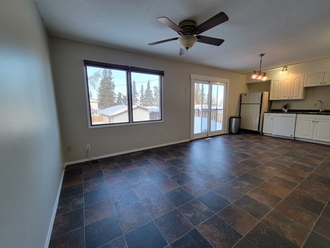 A room with a ceiling fan and sliding glass doors.