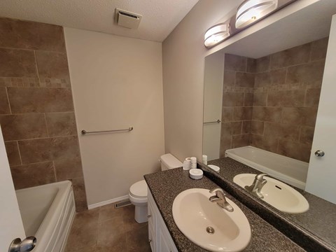 A bathroom with a tub, toilet, and sink.