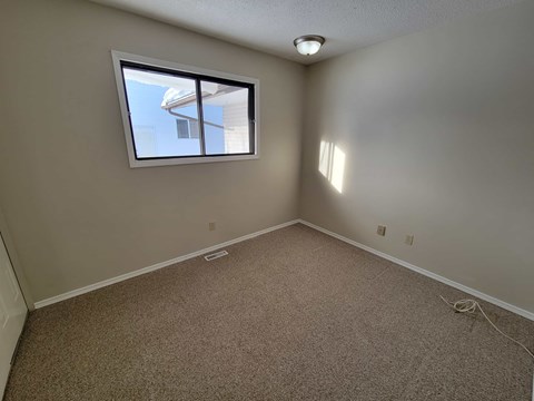 A room with a window and carpeted floor.