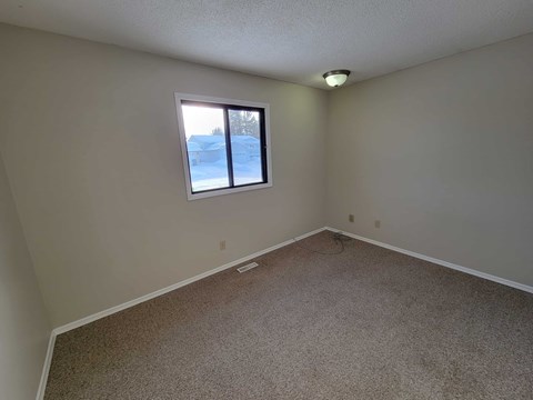 A room with a carpeted floor and a window showing a snowy landscape outside.
