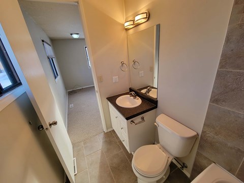 A bathroom with a toilet, sink, and mirror.