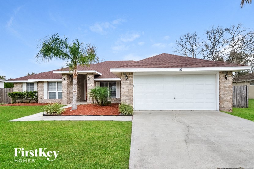 a home with a white garage door and a palm tree