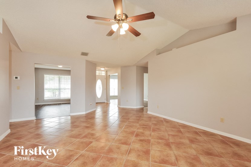 an empty living room with a ceiling fan and tile flooring