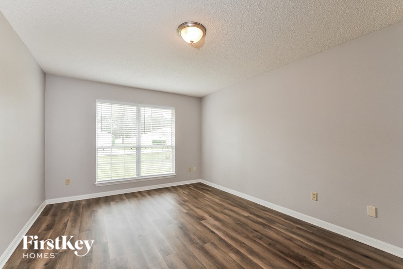 the spacious living room with wood flooring and a window