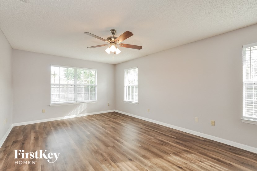 an empty living room with a ceiling fan and wood floors