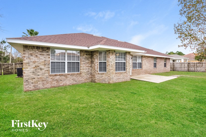a small brick house with a grassy yard and a patio