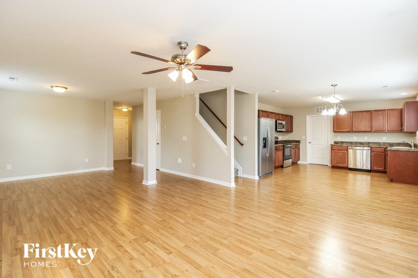 A spacious living room with wooden floors and a central fan.