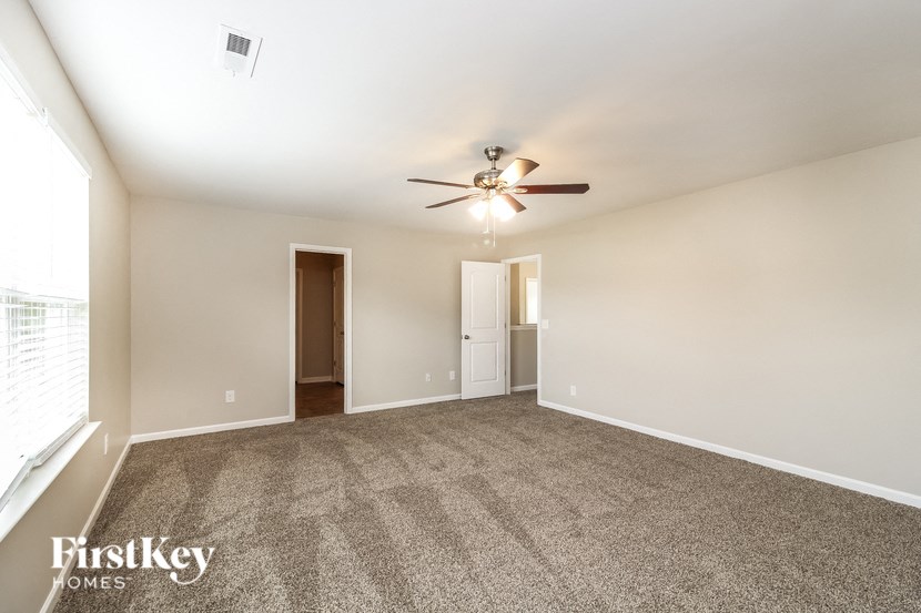 A spacious room with a ceiling fan and two doors.