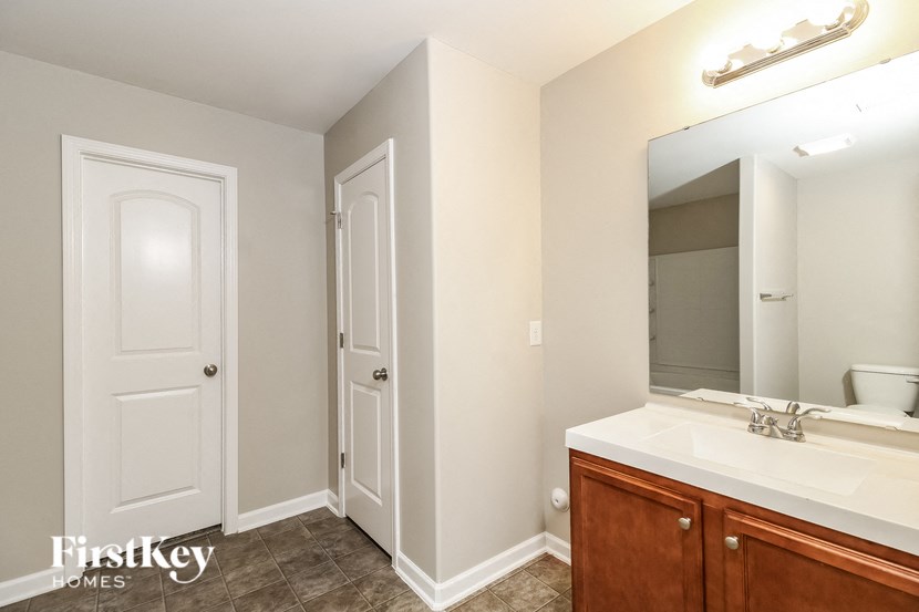 A bathroom with a sink, mirror, and two doors.