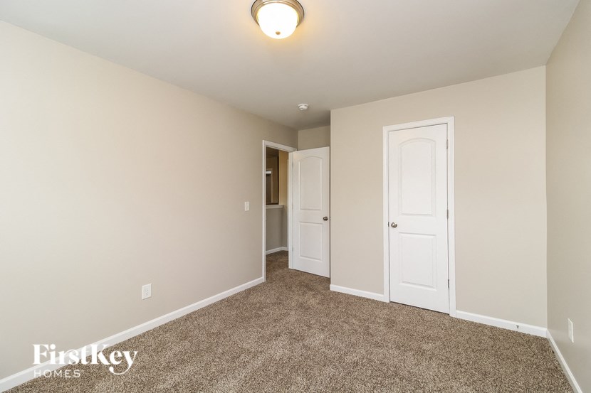 A carpeted room with a doorway leading to another room.