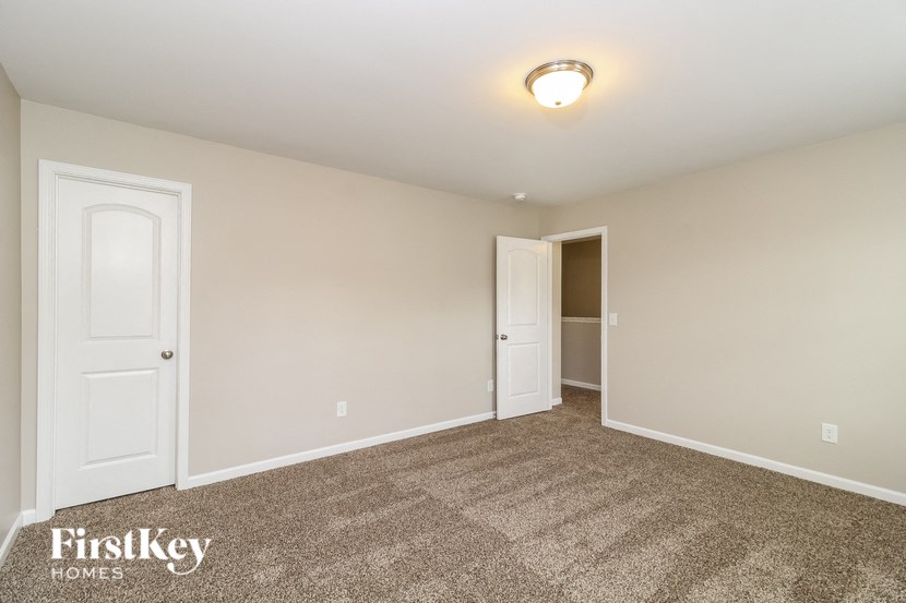 A room with a carpeted floor and two doors.