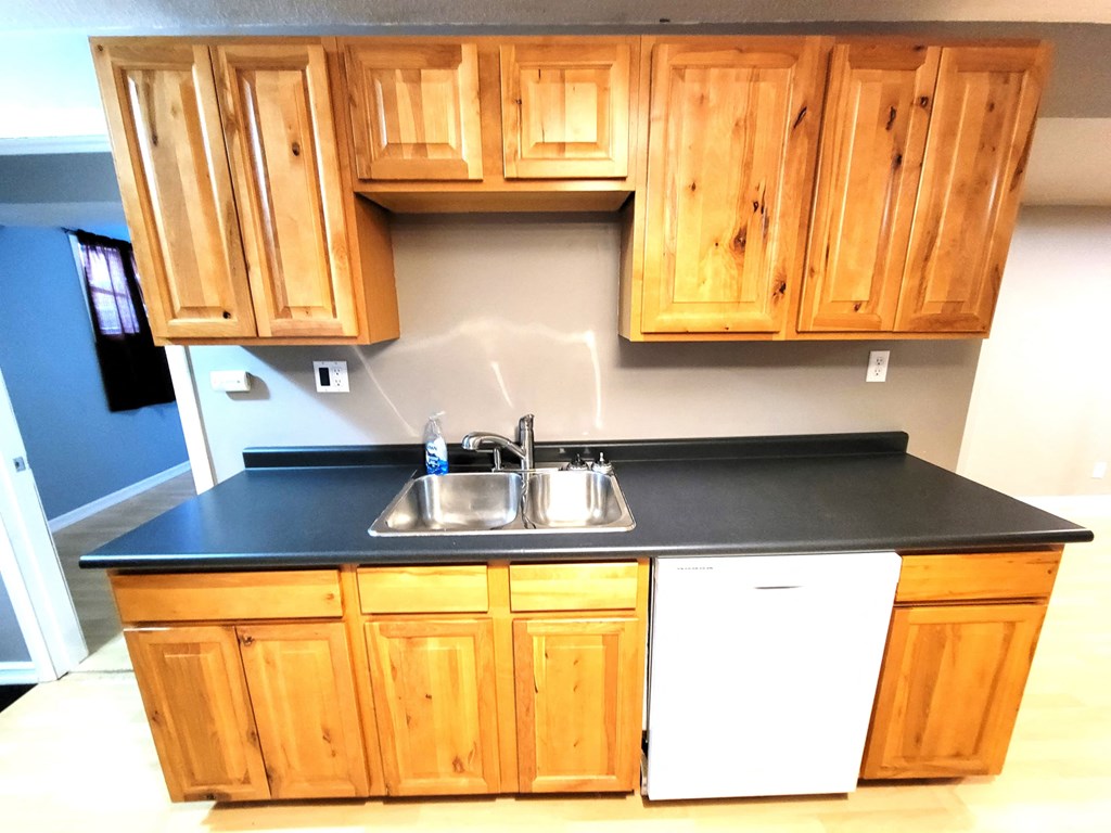 a kitchen with wooden cabinets and a black counter top